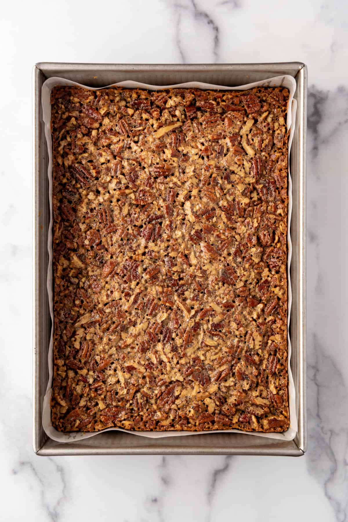 An overhead image of baked pecan pie bars in a pan.
