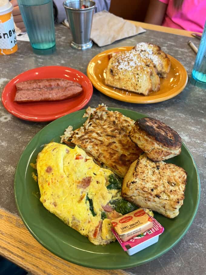 An omelette, biscuit, and hashbrowns on a plate.