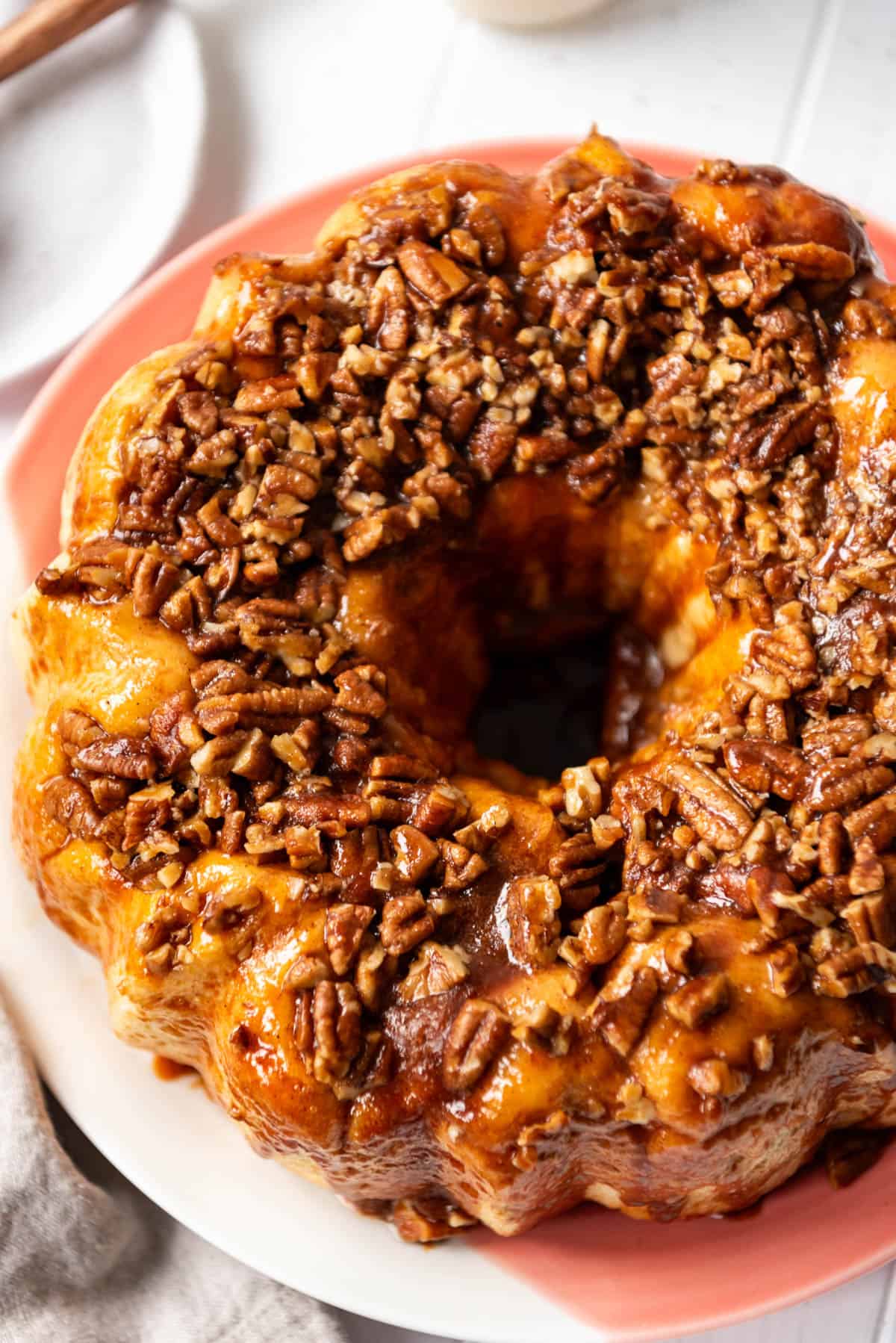 An overhead image of chopped pecans and caramel over monkey bread.