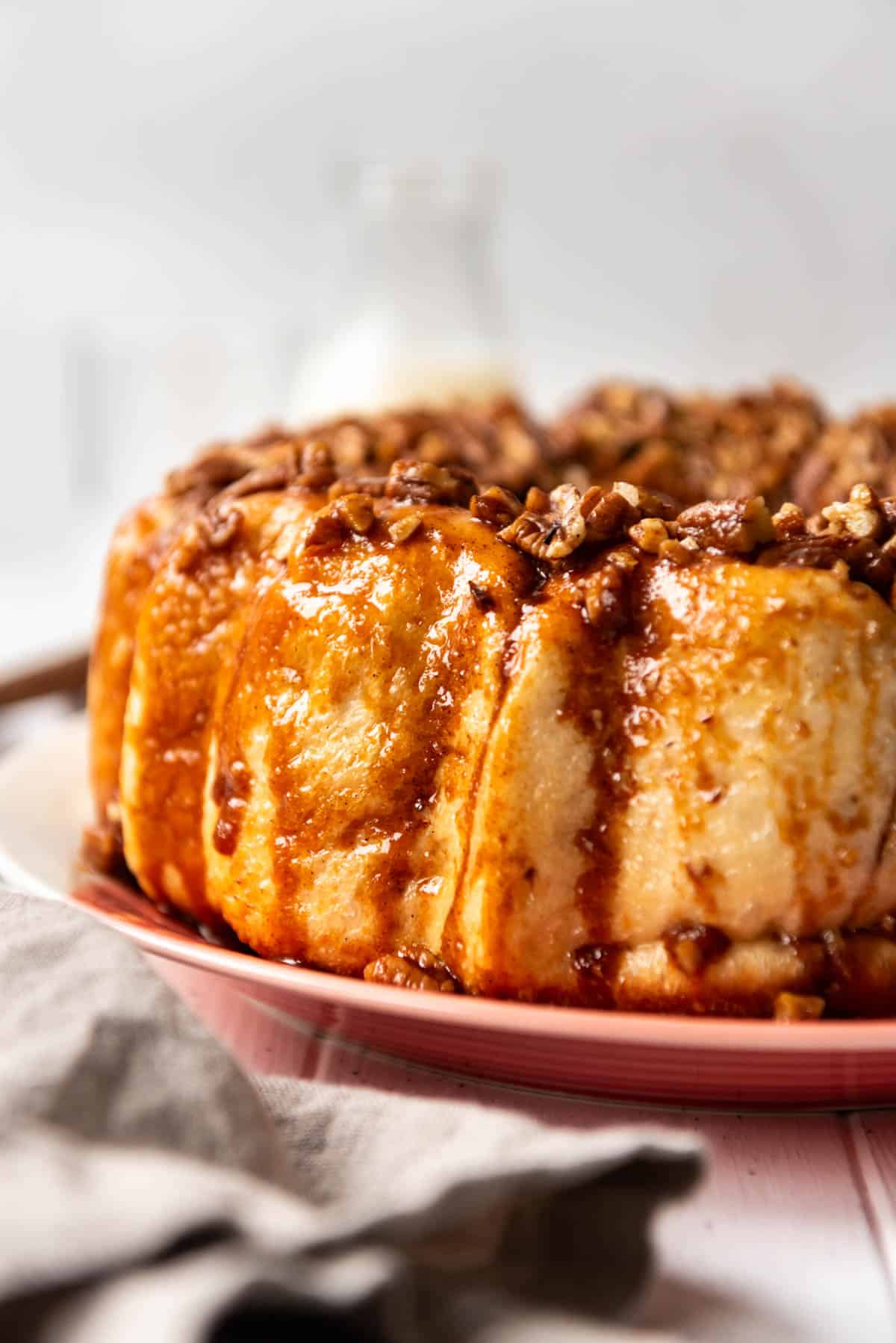 A side view of caramel pecan monkey bread on a pink plate.