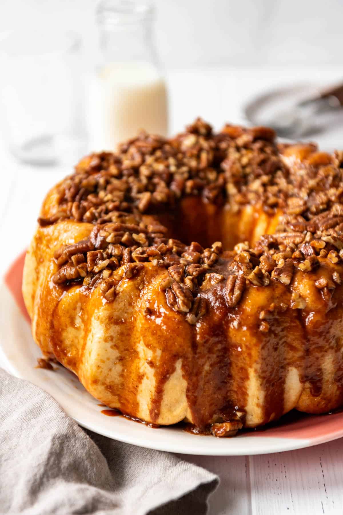A side angle of caramel dripping down the sides of monkey bread on a plate.