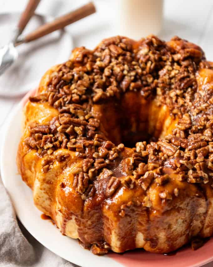An image of easy monkey bread made with butterscotch pudding and frozen roll dough on a serving plate in front of a jar o f milk and forks.