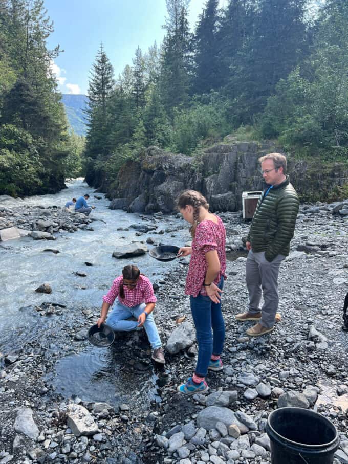 A dad and two kids next to a river panning for gold in Girdwood, Alaska.