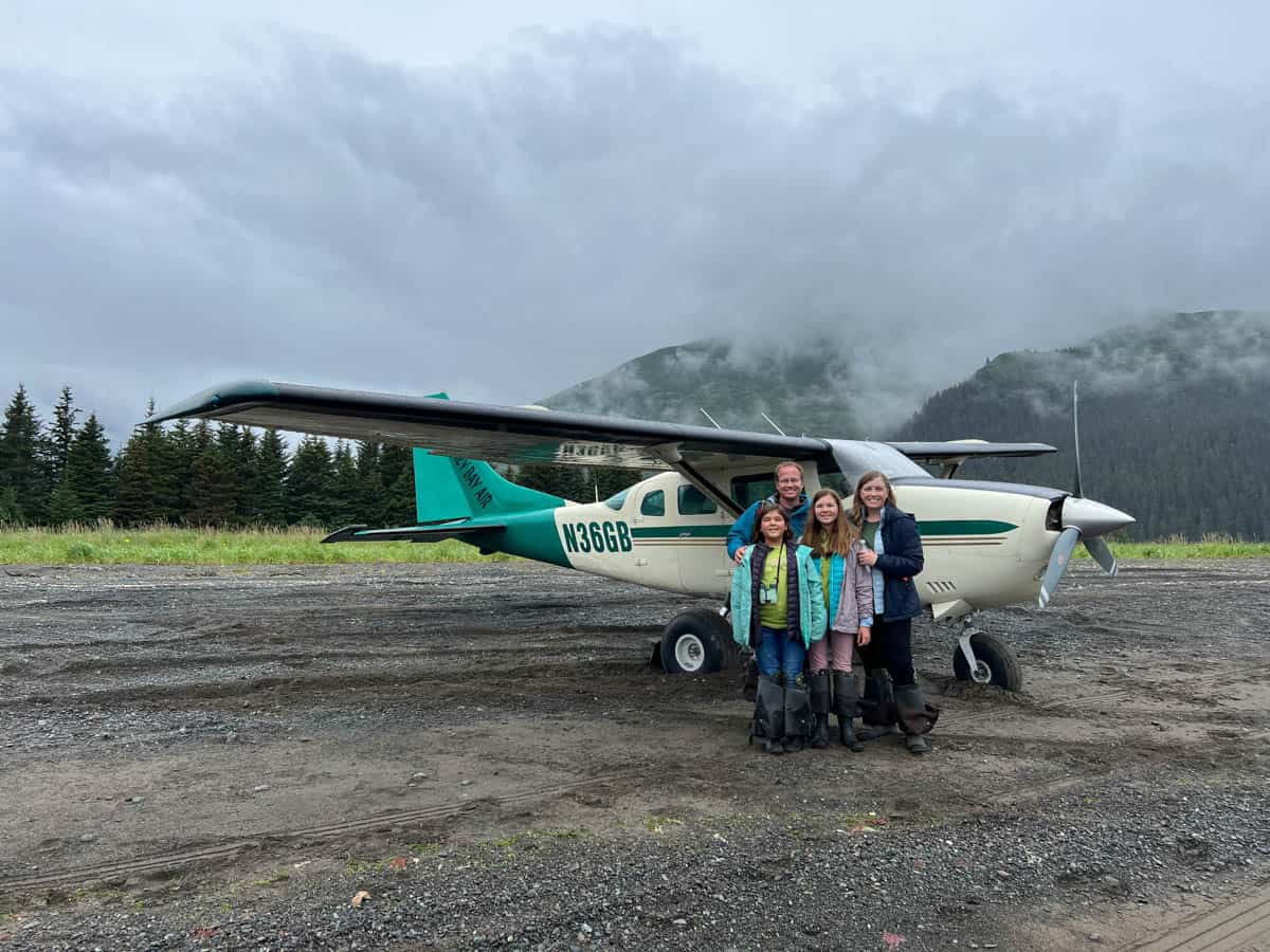 An image of a family in front of a bush plane on a beach in Chinitna Bay in Lake Clark National Park.