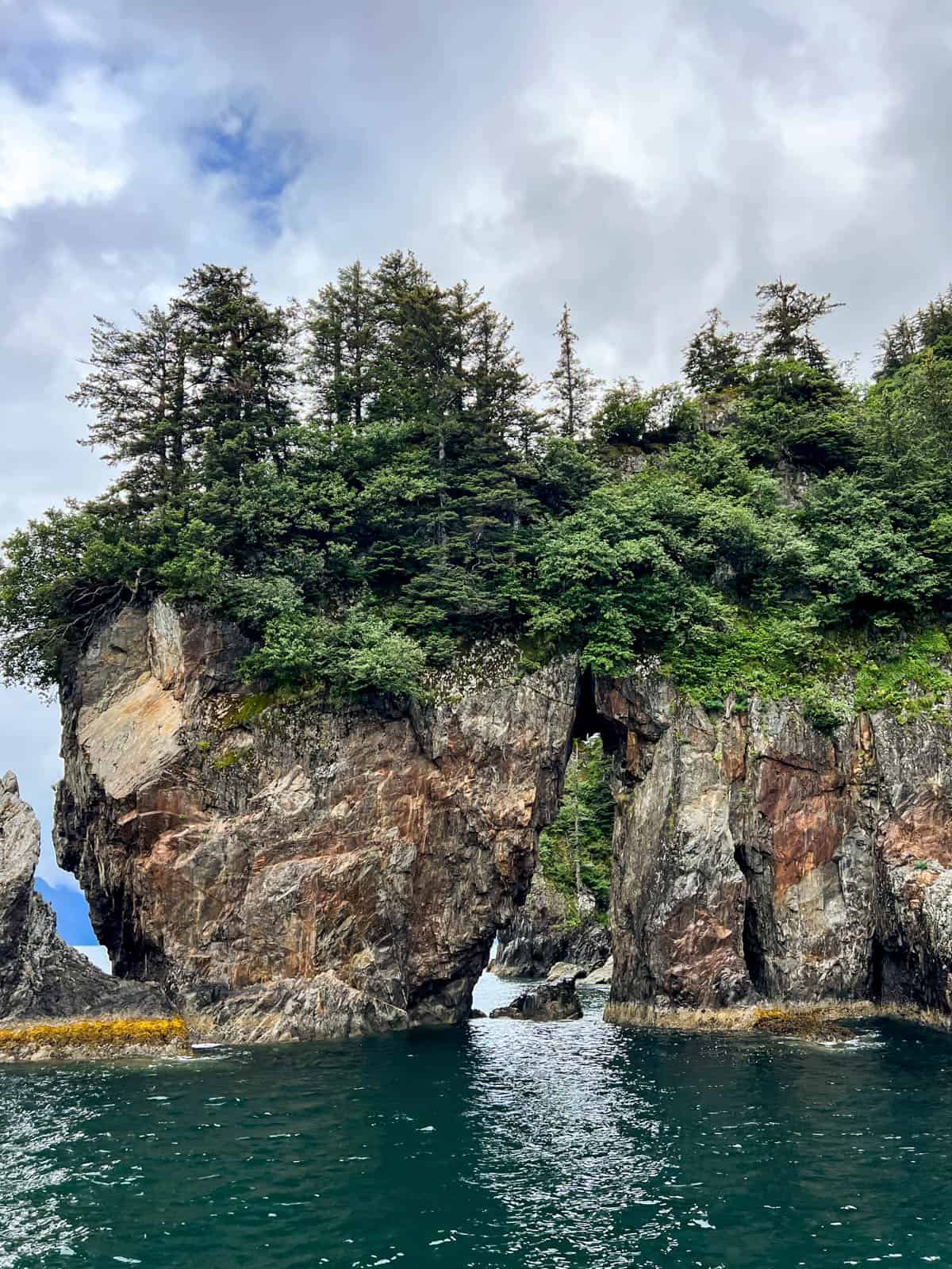 A rock formation with an arch over the water in Kenai Fjiords National Park.