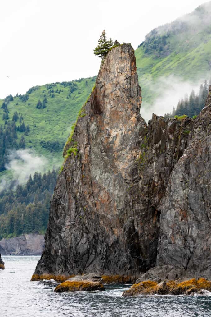An image of a tall rock formation jutting out of the water in Kenai Fjiords National Park.