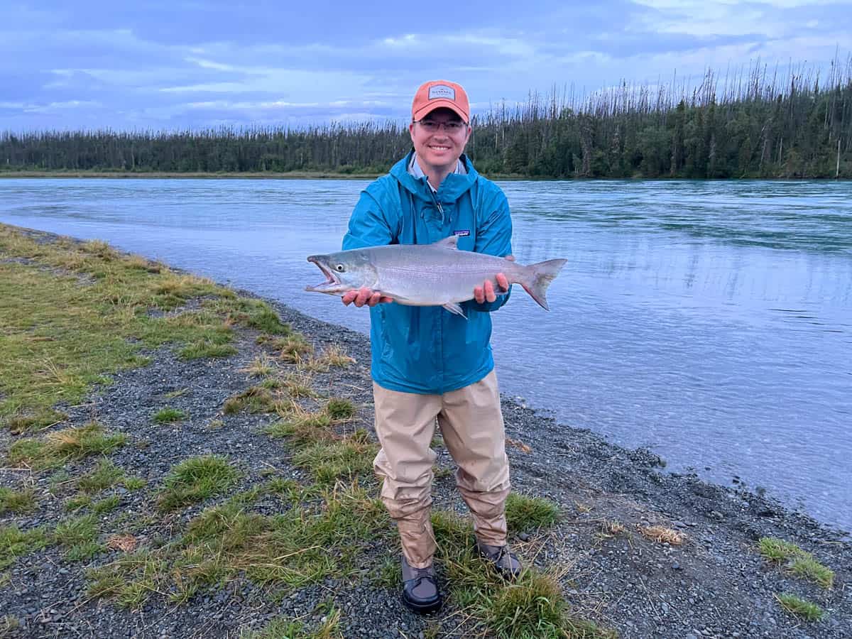 A man holding a fish he caught on the Kenai River.