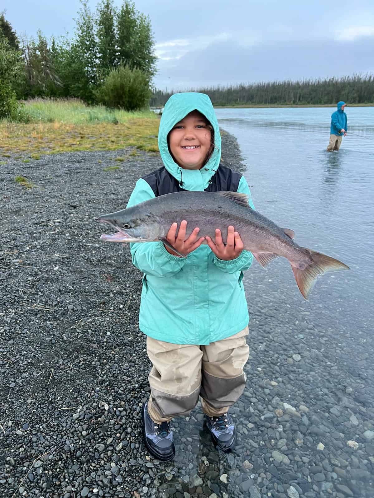 A picture of a girl holding a fish she caught on the Kenai river in Alaska.