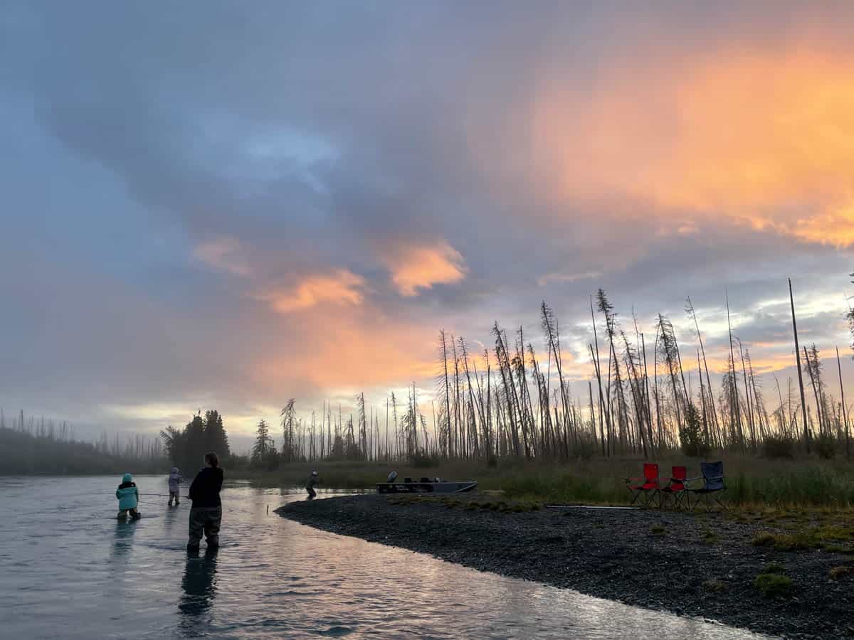 An image of sunrise over a river on the Kenai in Alaska with people fishing.