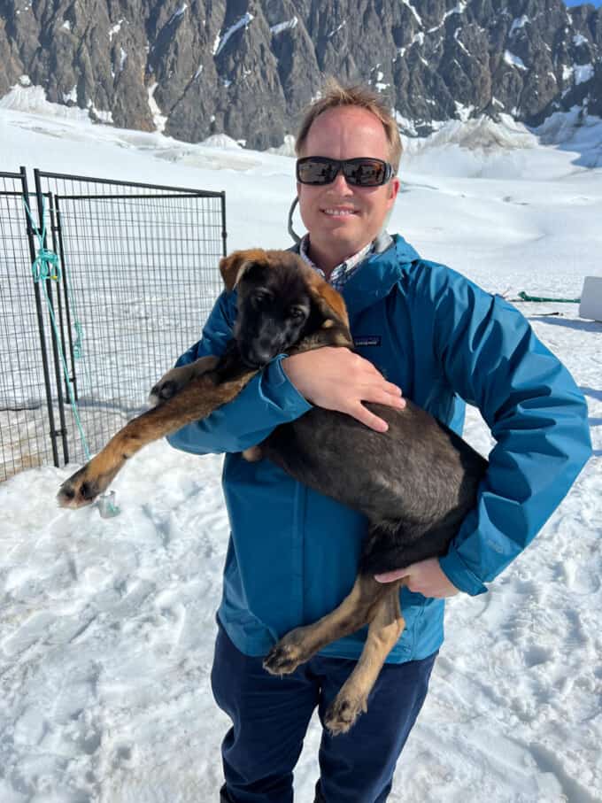 A man holding a sled dog puppy.