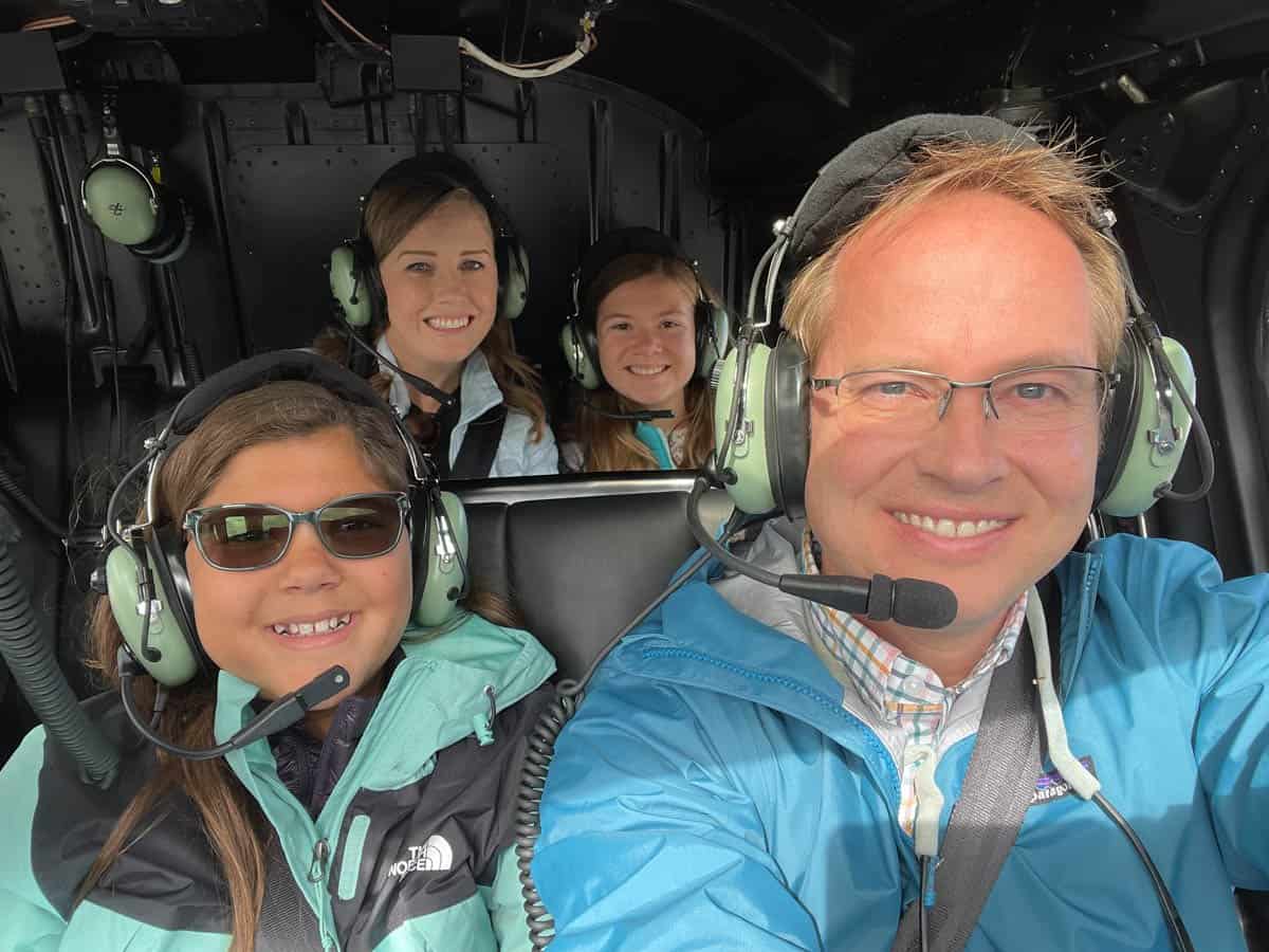 A family of two parents and two children in a helicopter with headphones on.