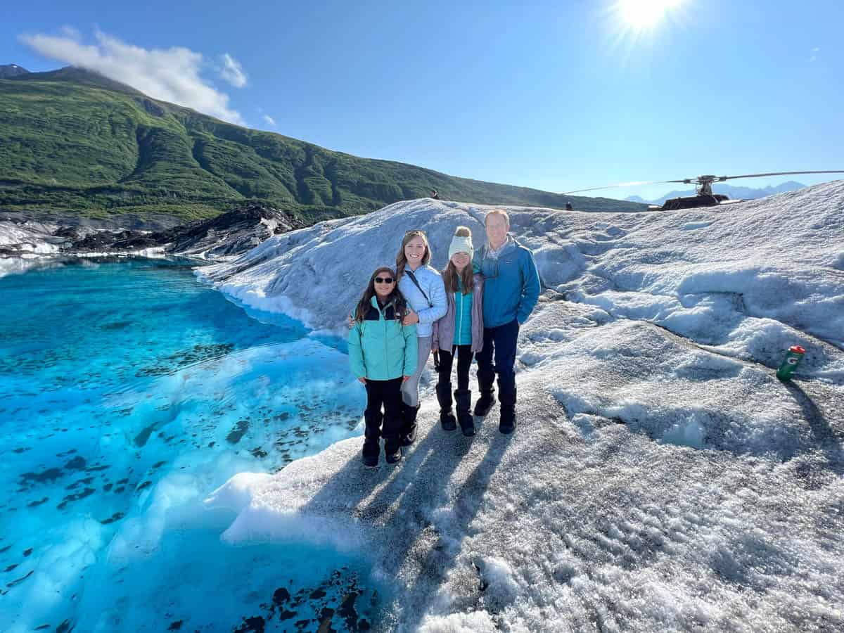 An image of a family in front of a glacial pool on the Knik Glacier.
