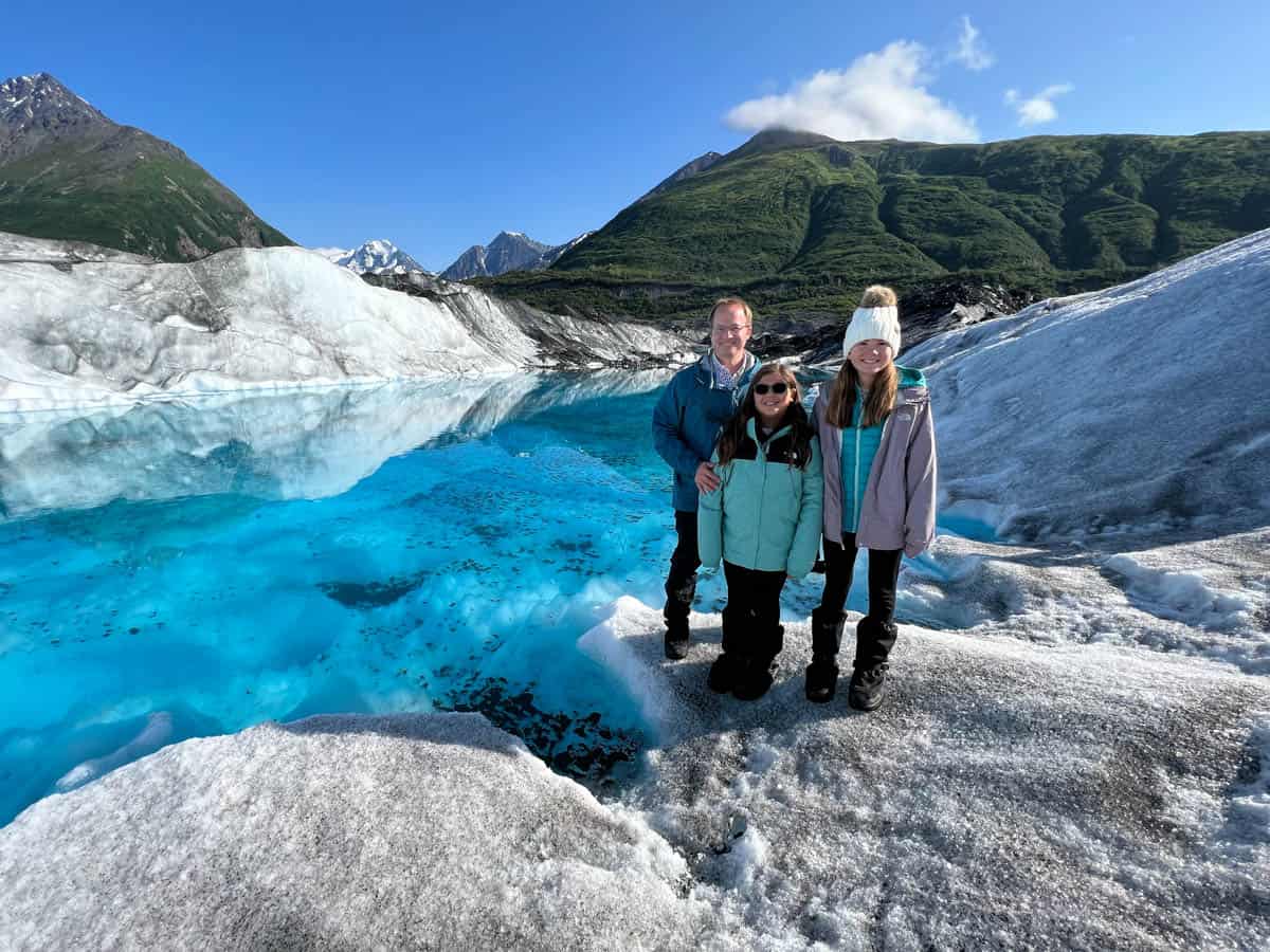 A dad and two daughters in front of a glacial lake.