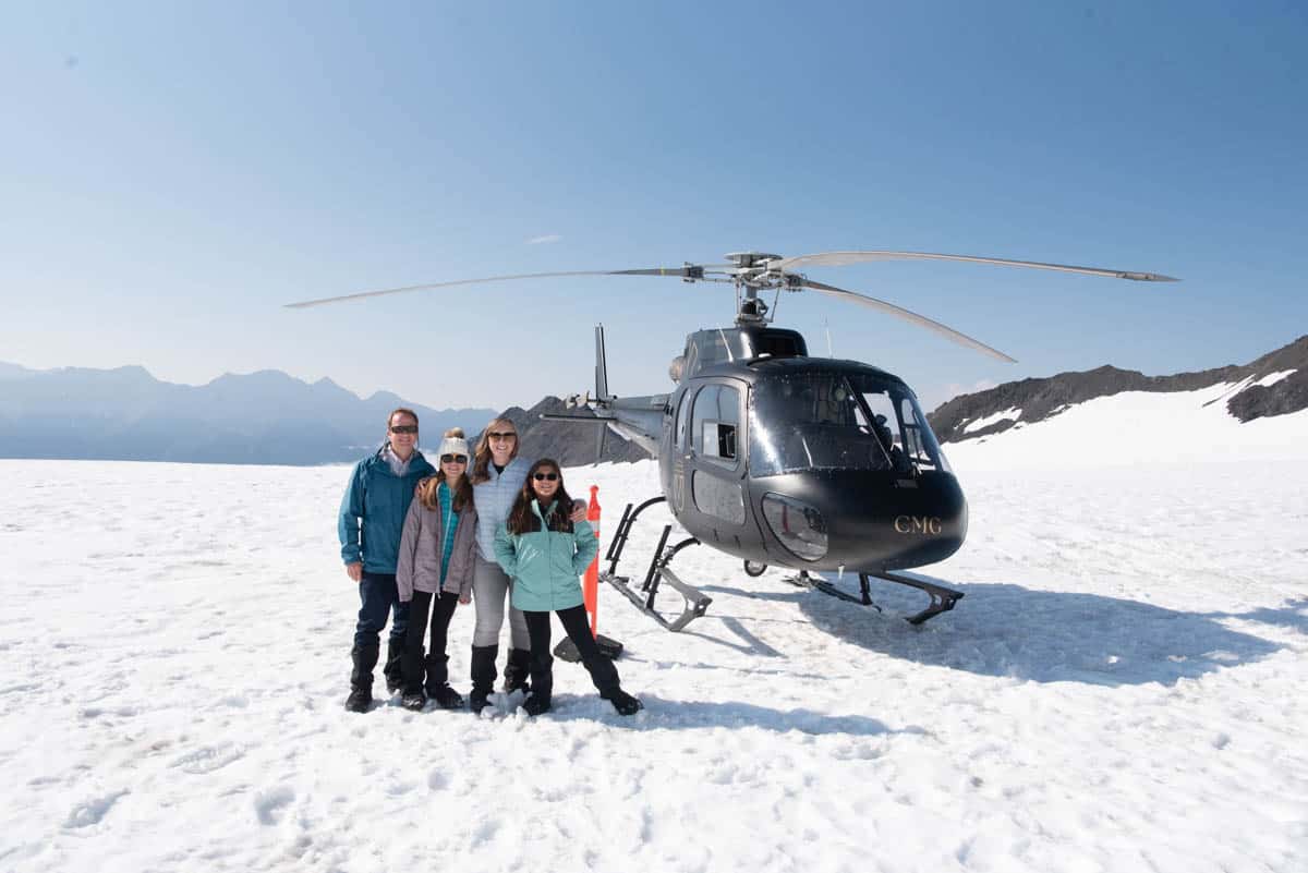 A family in front of a helicopter on a glacier in Alaska.