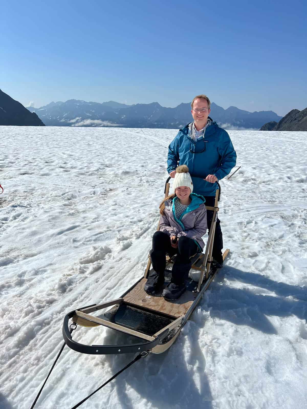 A dad and daughter on a dogsled.