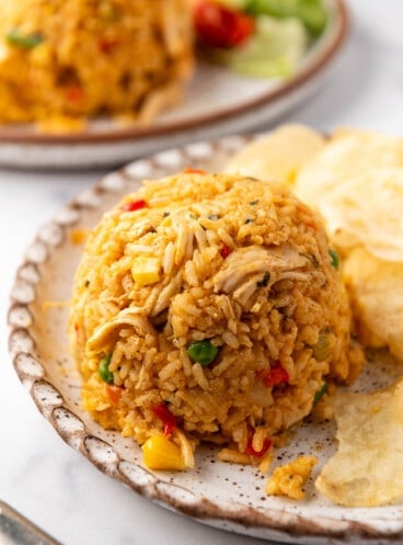 A close image of arroz con pollo on a plate with potato chips.