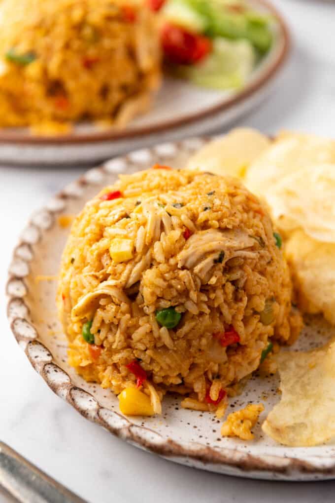 A close image of arroz con pollo on a plate with potato chips.