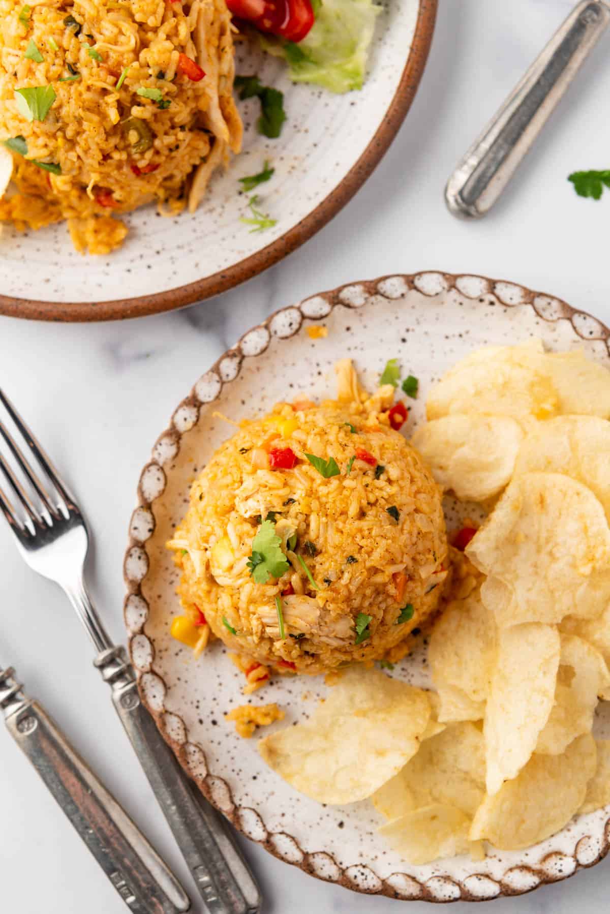 An overhead image of plates of arroz con pollo with potato chips.