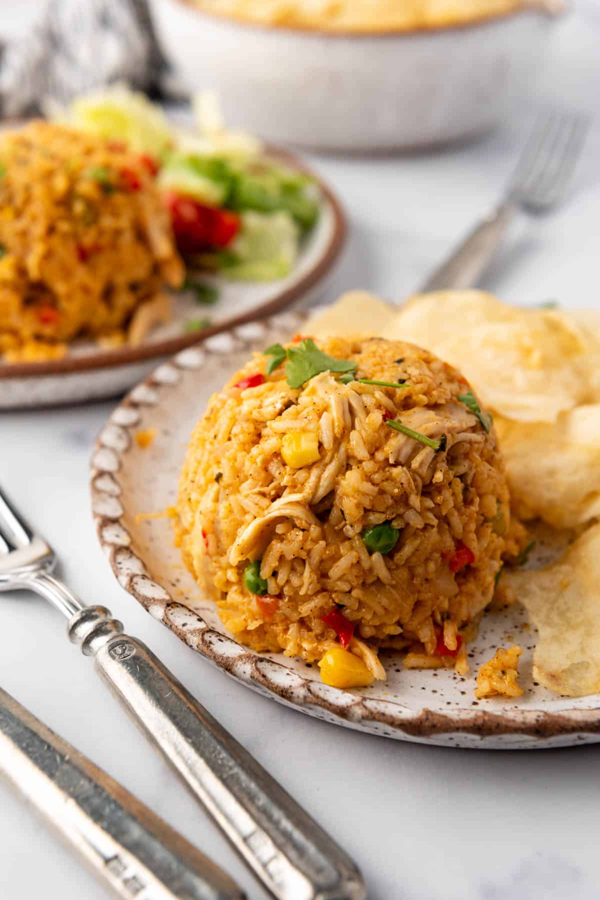 Images of plates with mounds of arroz on pollo and potato chips on them.