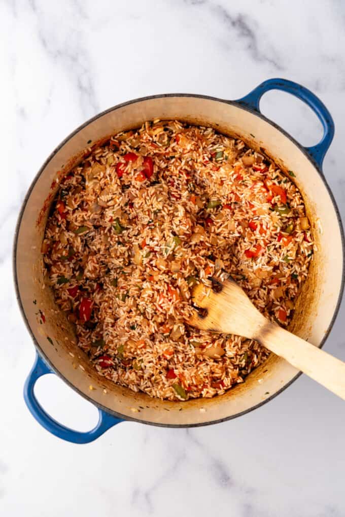 Ingredients for arroz con pollo stirred together in a pot.