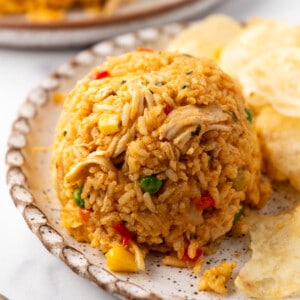 An image of a mound of Costa Rican arroz con pollo on a plate with potato chips.