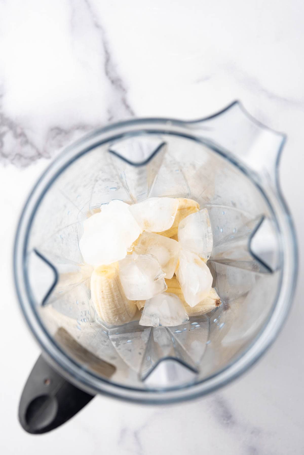 An overhead image of a pitcher with ice, bananas, and milk in it.