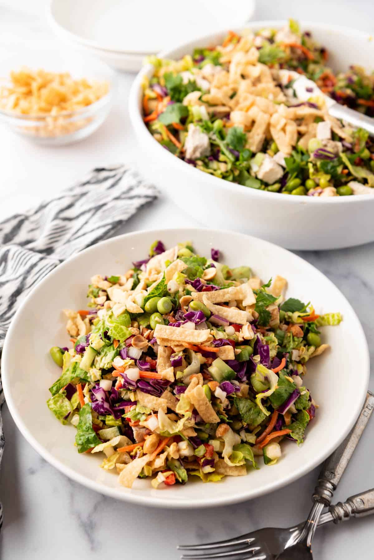 A plate of Thai chicken salad in front of a big bowl of the rest of the salad.