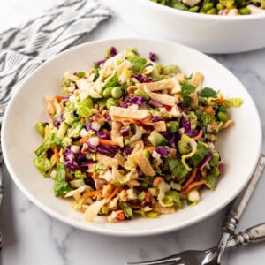 A plate of Thai chicken salad in front of a big bowl of the rest of the salad.