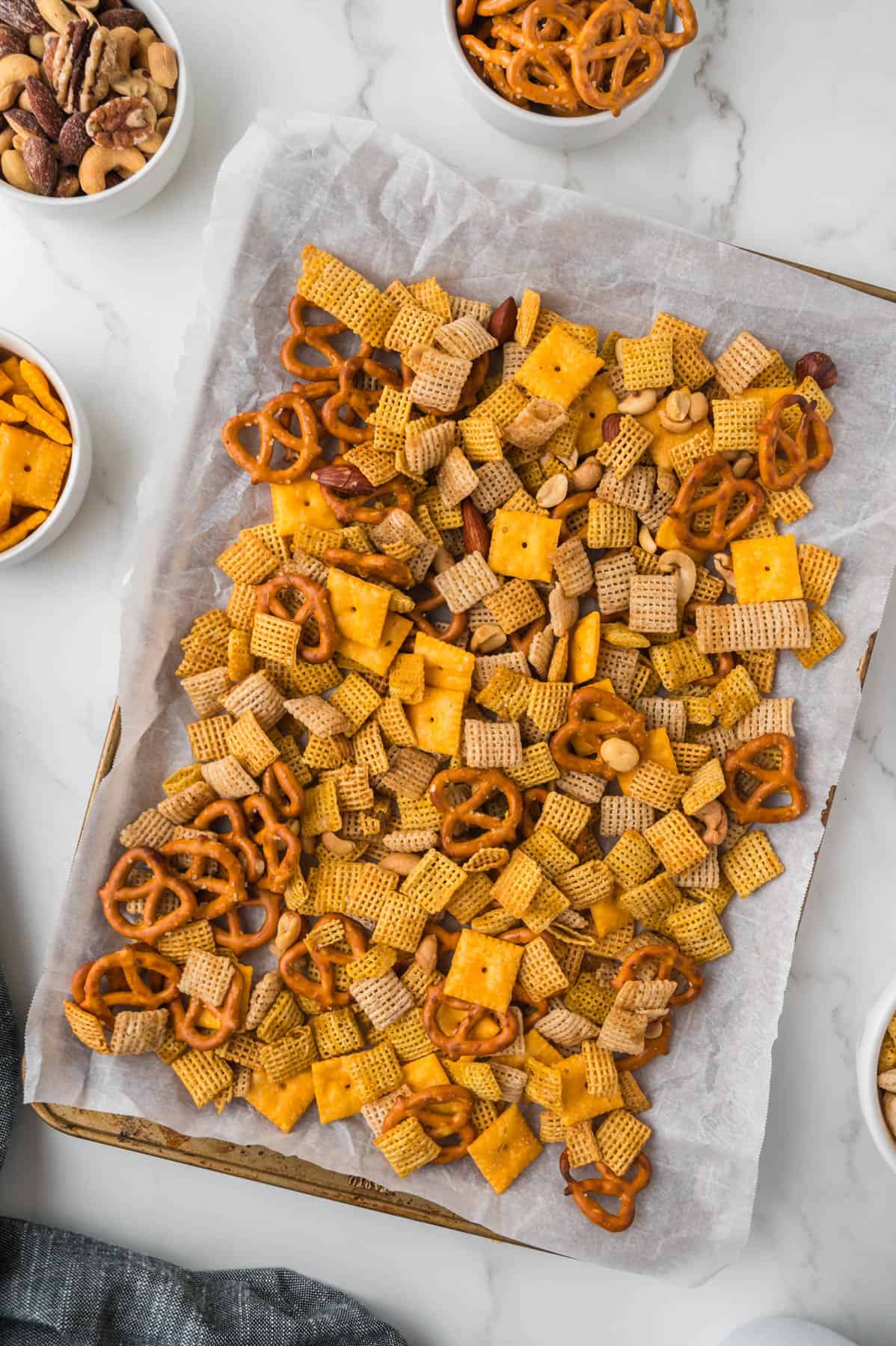 Baked chex mix on a baking sheet lined with parchment paper.