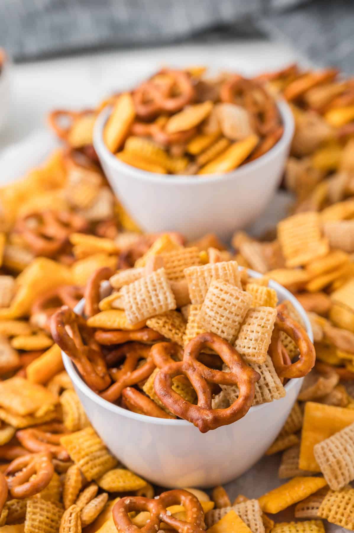 Two white bowls piled with Chex mix.