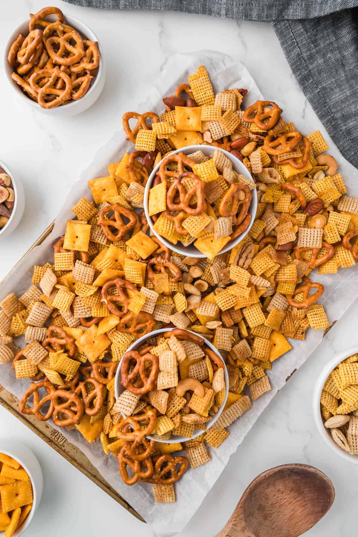 An overhead image of bowls of homemade chex mix on a baking sheet full of more chex mix.