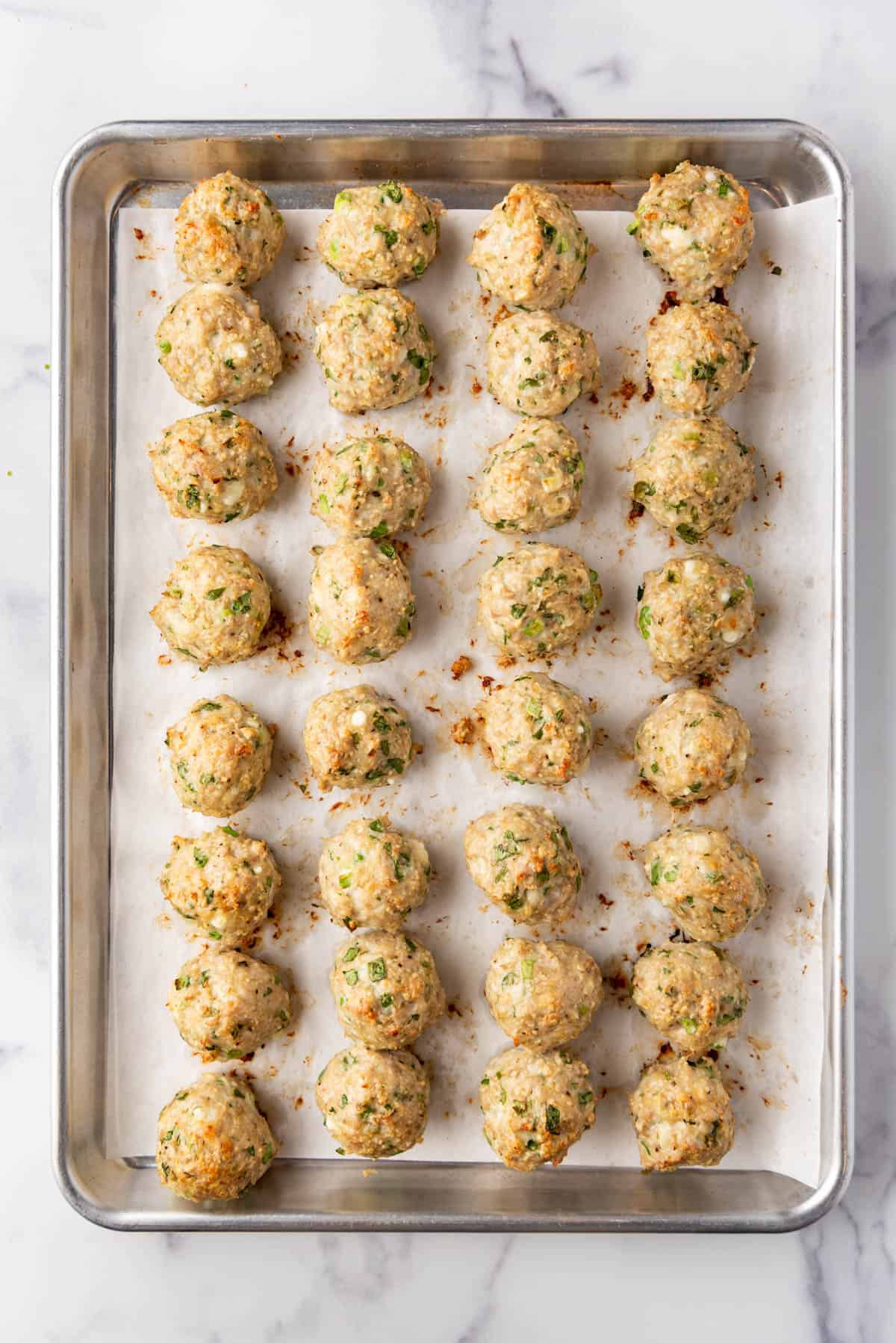 Baked chicken meatballs on a baking sheet.