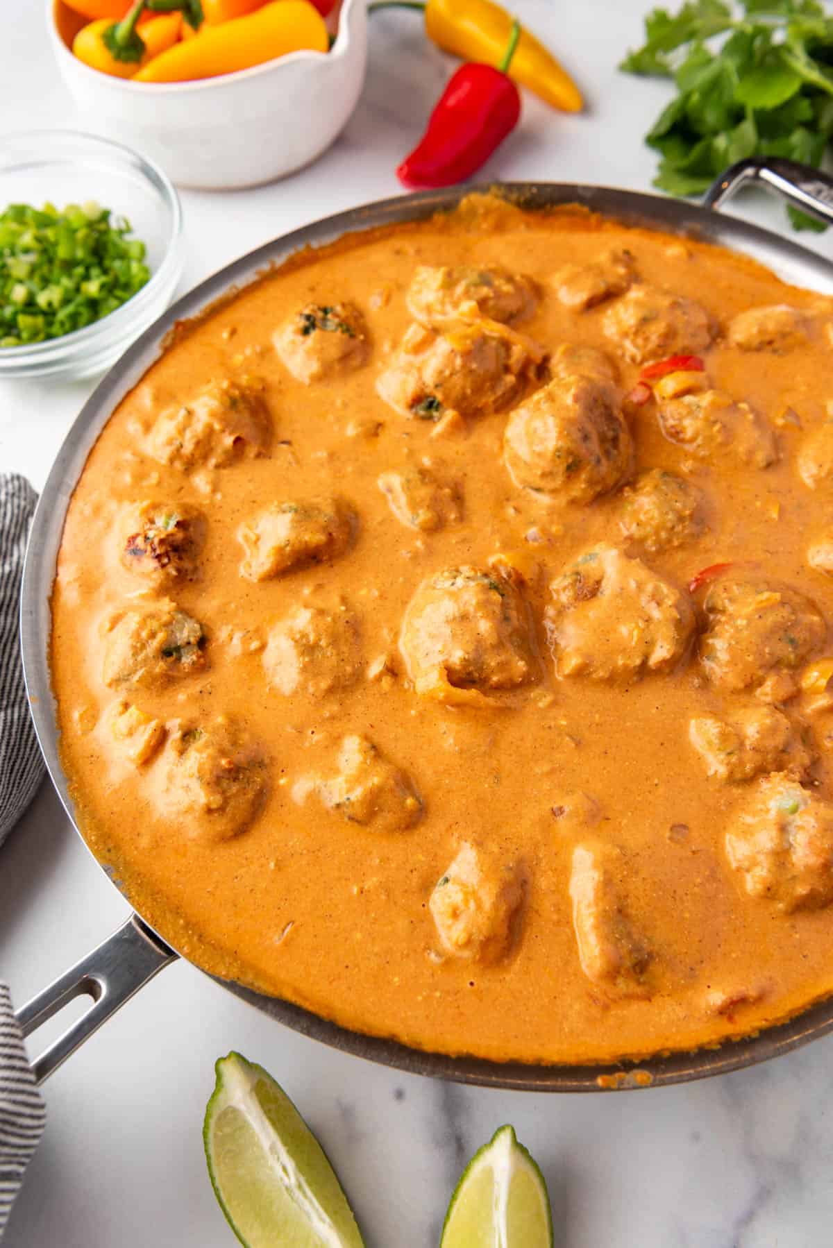 A large pan of chicken meatballs in coconut curry sauce.