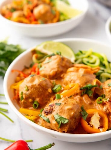 A close up image of a bowl of coconut curry chicken meatballs.