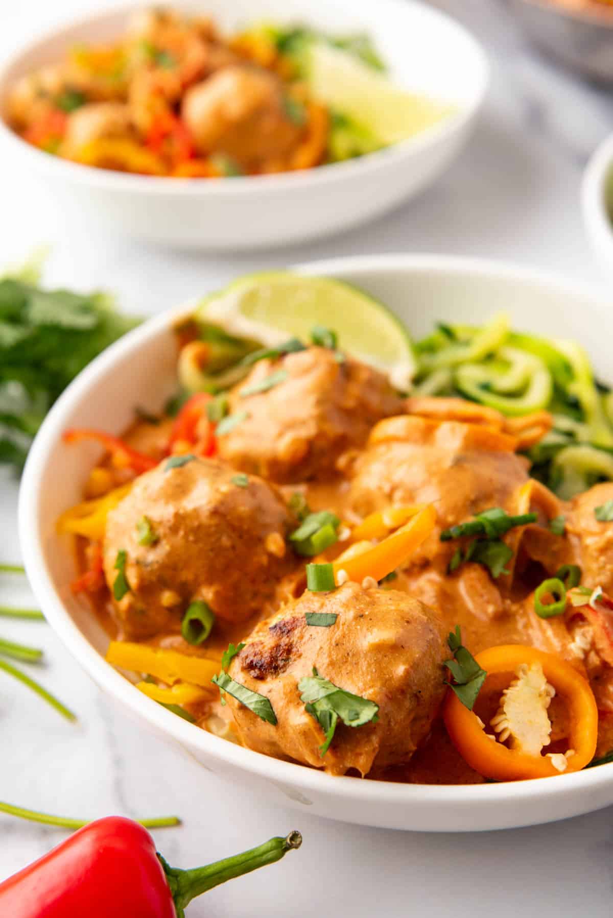 A close up image of a bowl of coconut curry chicken meatballs.