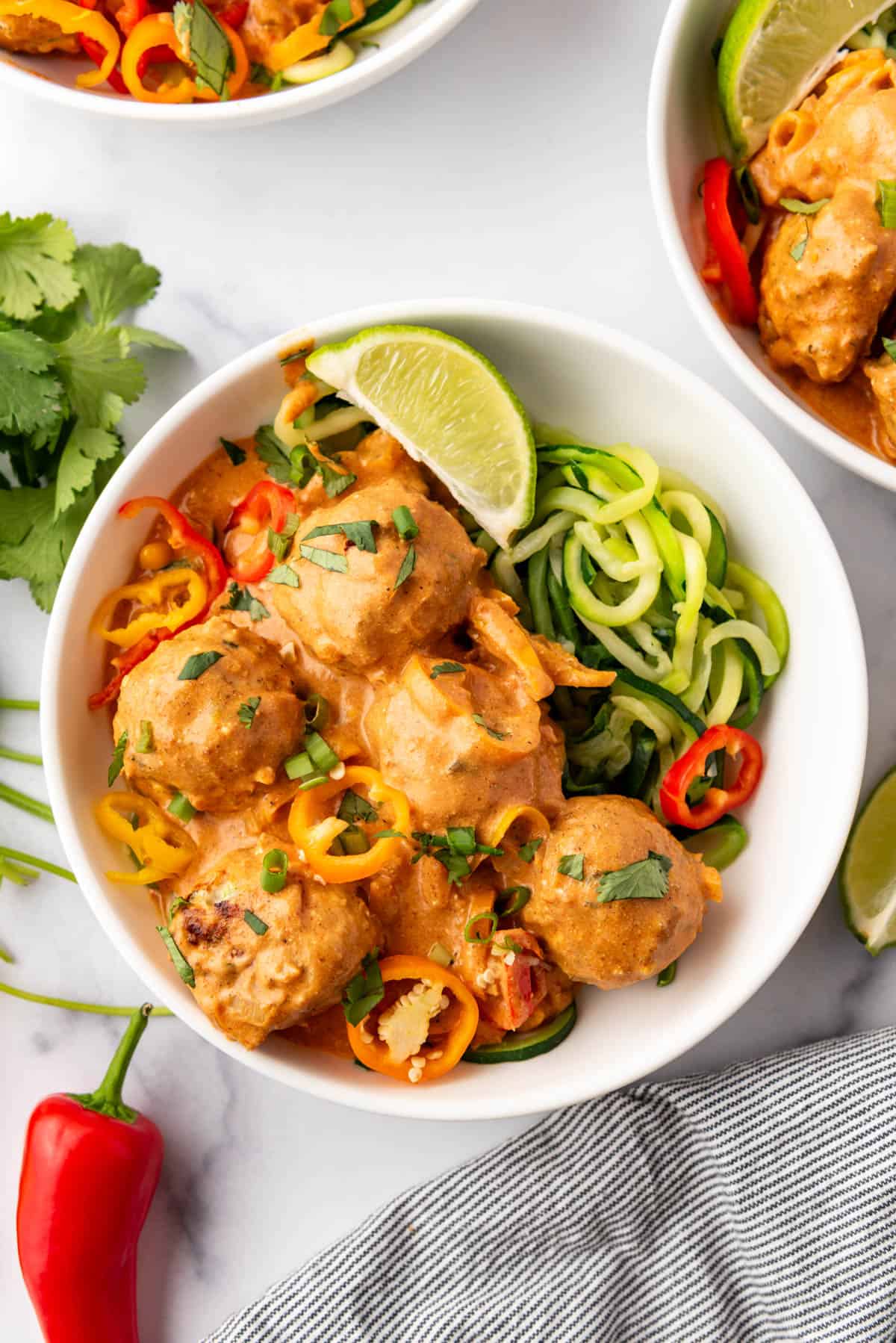 An overhead image of a bowl of coconut curry chicken meatballs.