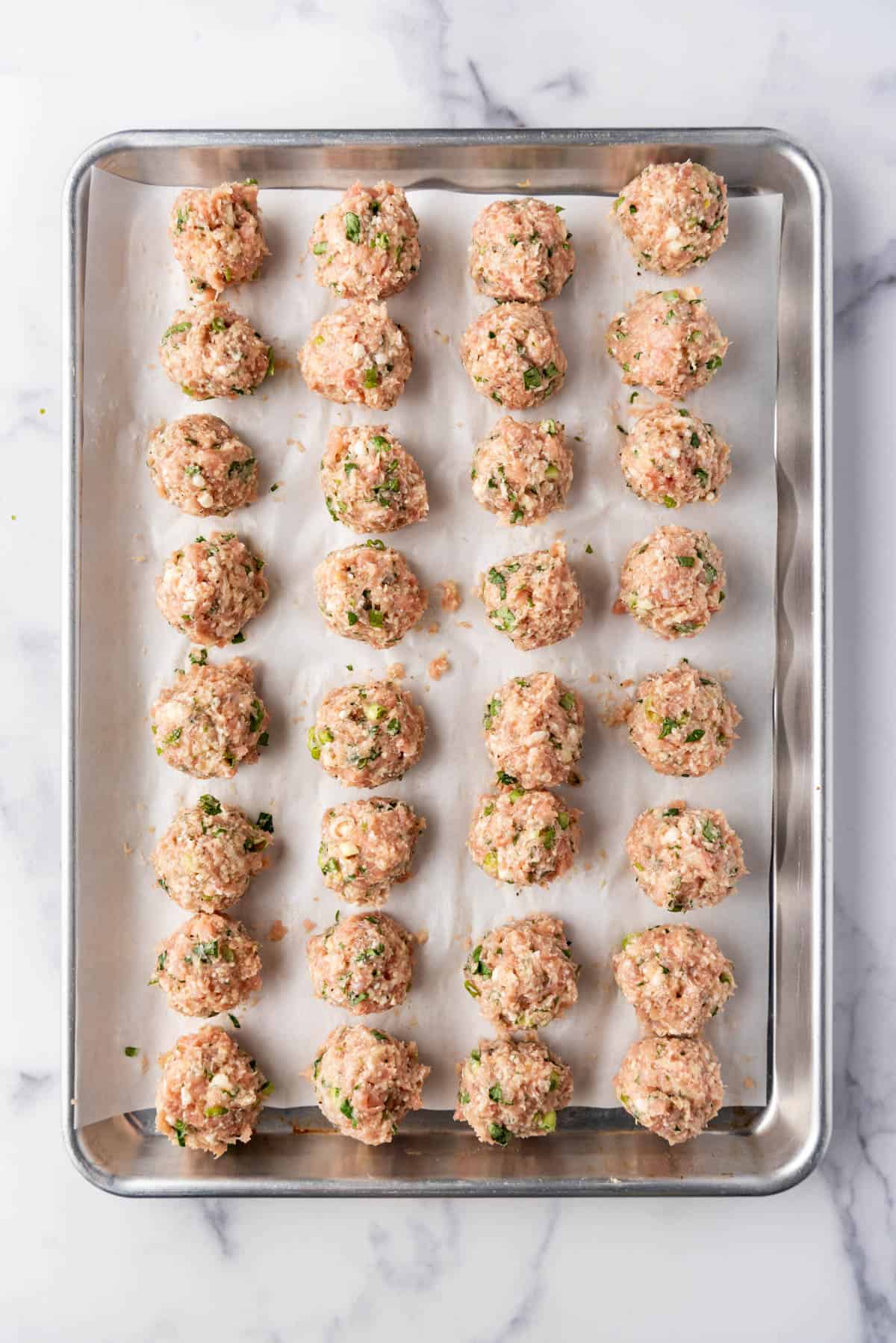 Chicken meatball mixture on a baking sheet ready to go into the oven.