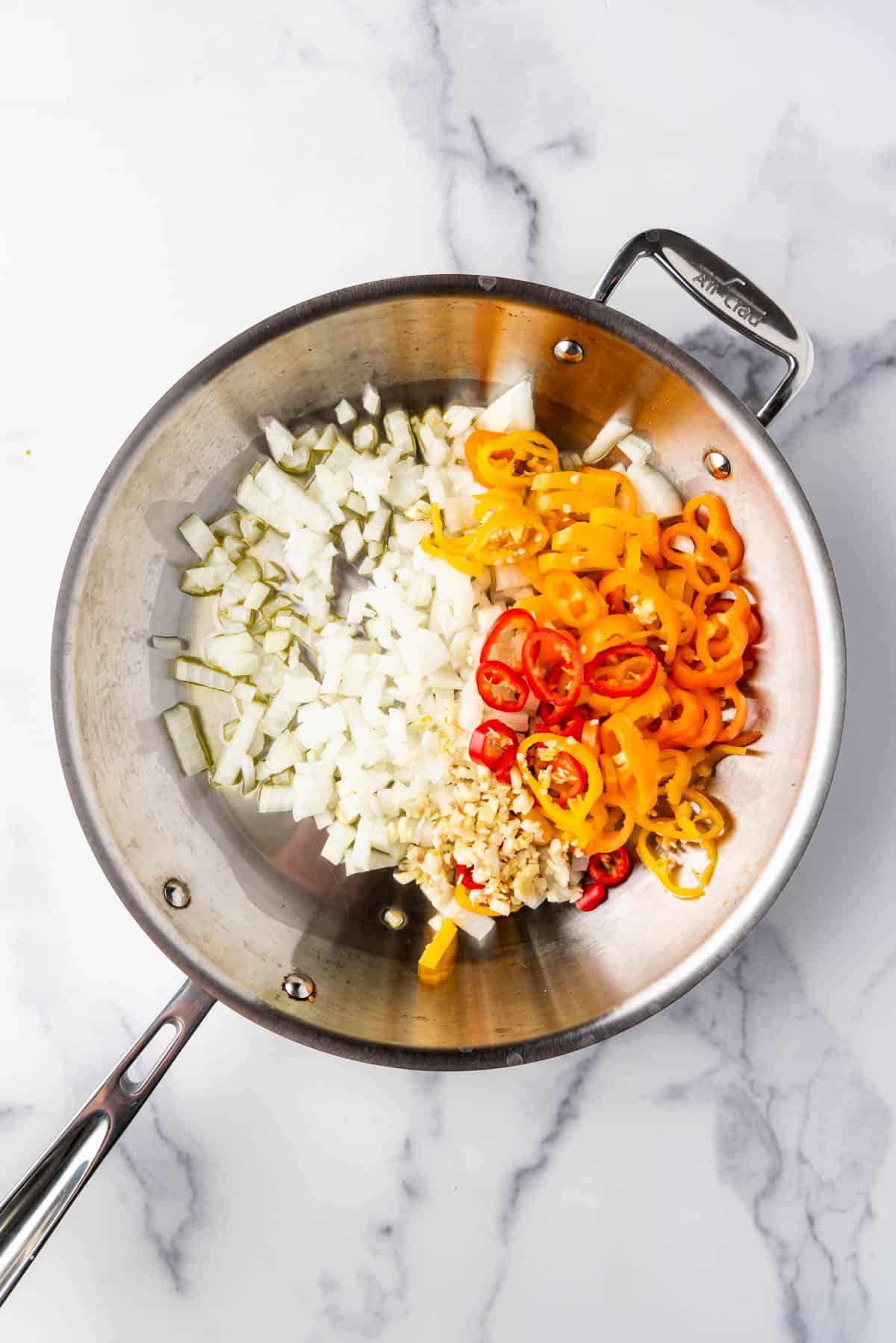 An image of chopped onions, peppers, and garlic in a pan.