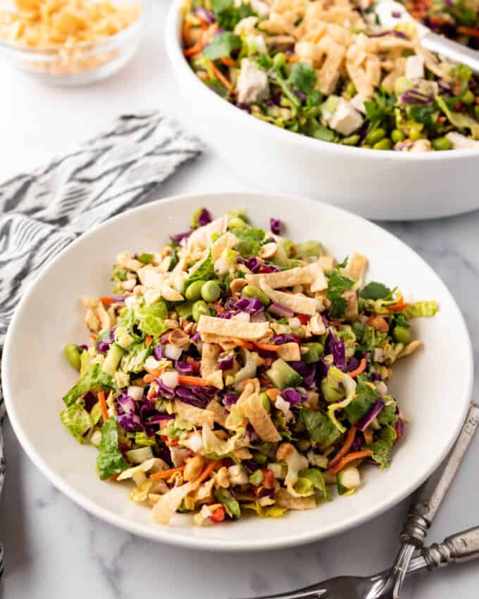 A plate of Thai chicken salad in front of a big bowl of the rest of the salad.