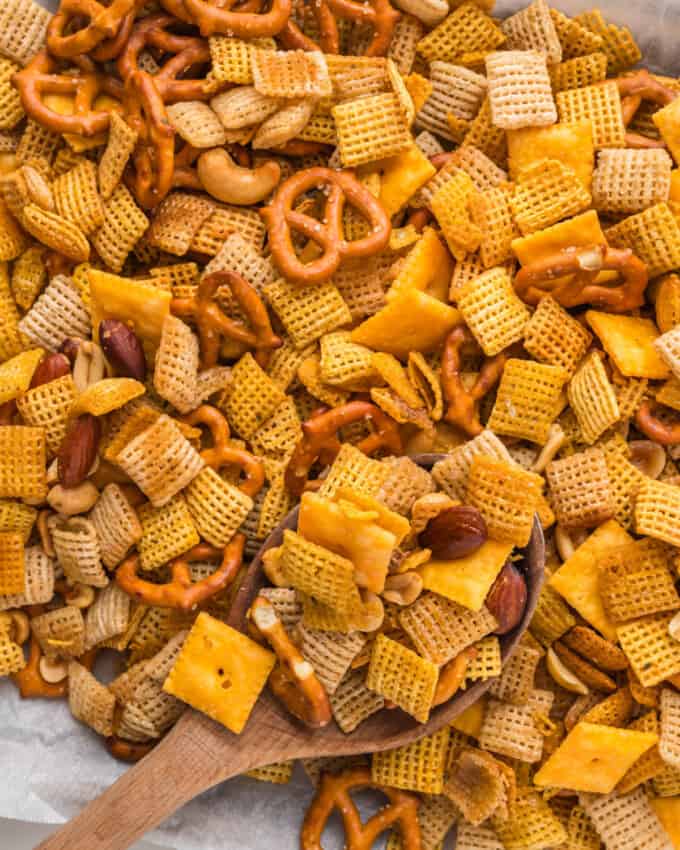 An overhead image of a wooden spoon in a pan of homemade chex mix.