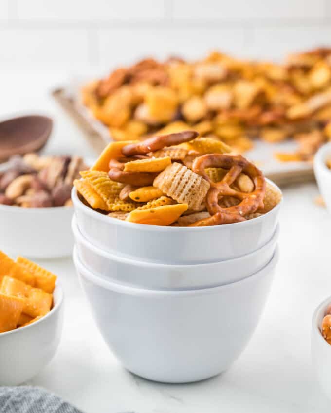 An image of stacked white bowls holding chex mix.