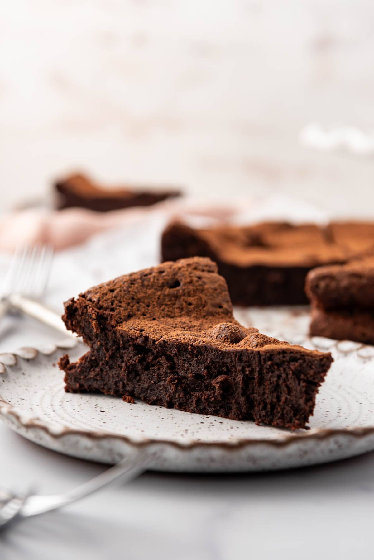 An image of a slice of flourless chocolate cake on a plate.