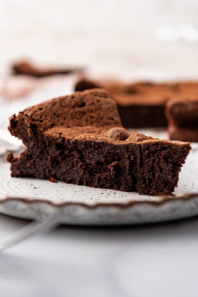 A close up image of a slice of flourless chocolate cake on a plate.