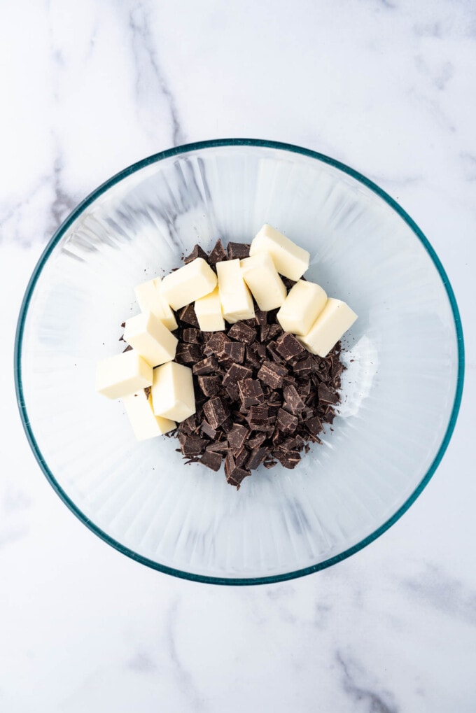 Chopped chocolate and cubed butter in a glass mixing bowl.