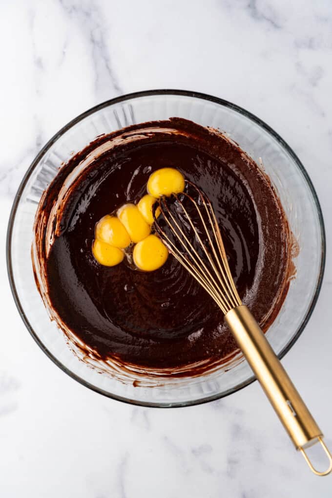 Adding egg yolks to chocolate cake batter.