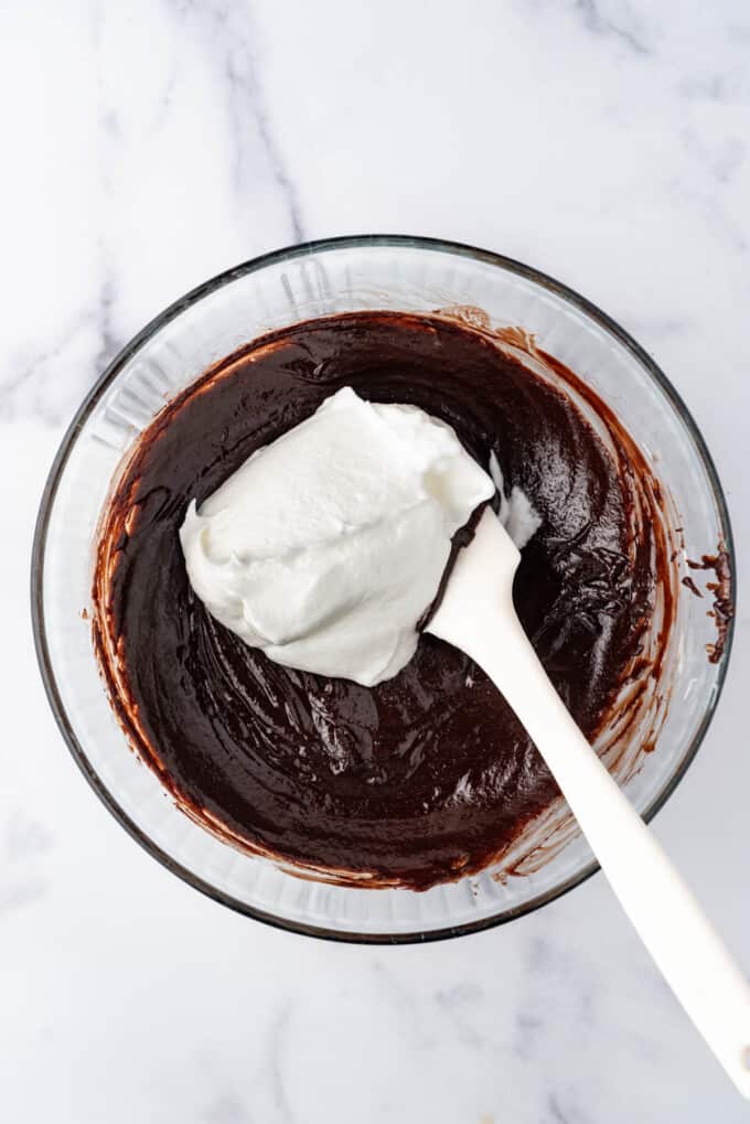 Adding some of the whipped egg whites to flourless chocolate cake batter.