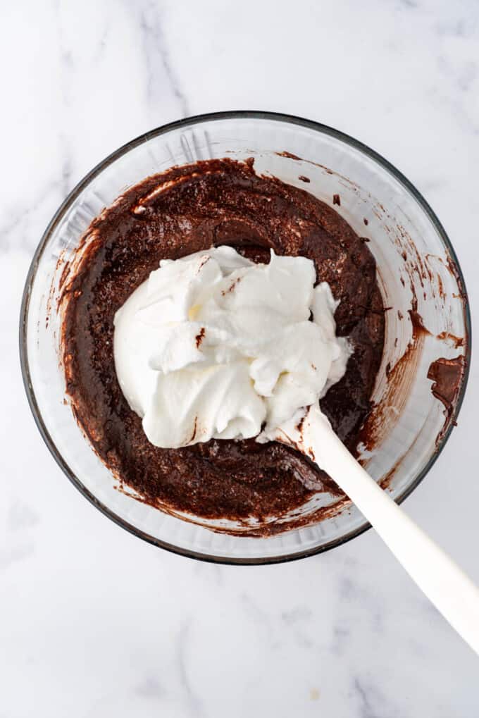 Folding in the remainder of stiff egg whites into chocolate cake batter.