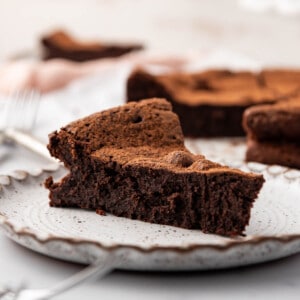 An image of a slice of flourless chocolate cake on a plate.