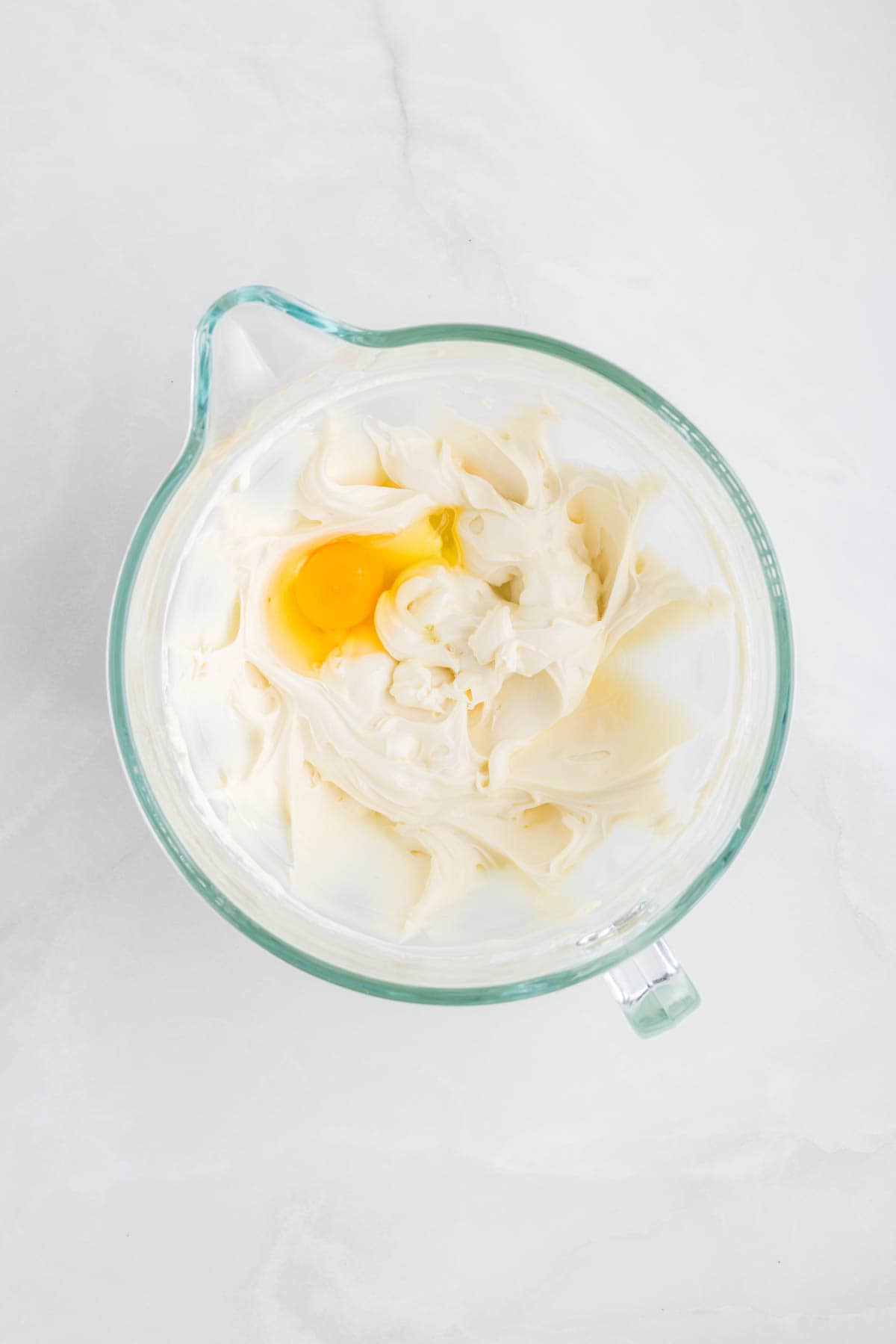 Creamed cream cheese in a large bowl with an egg.