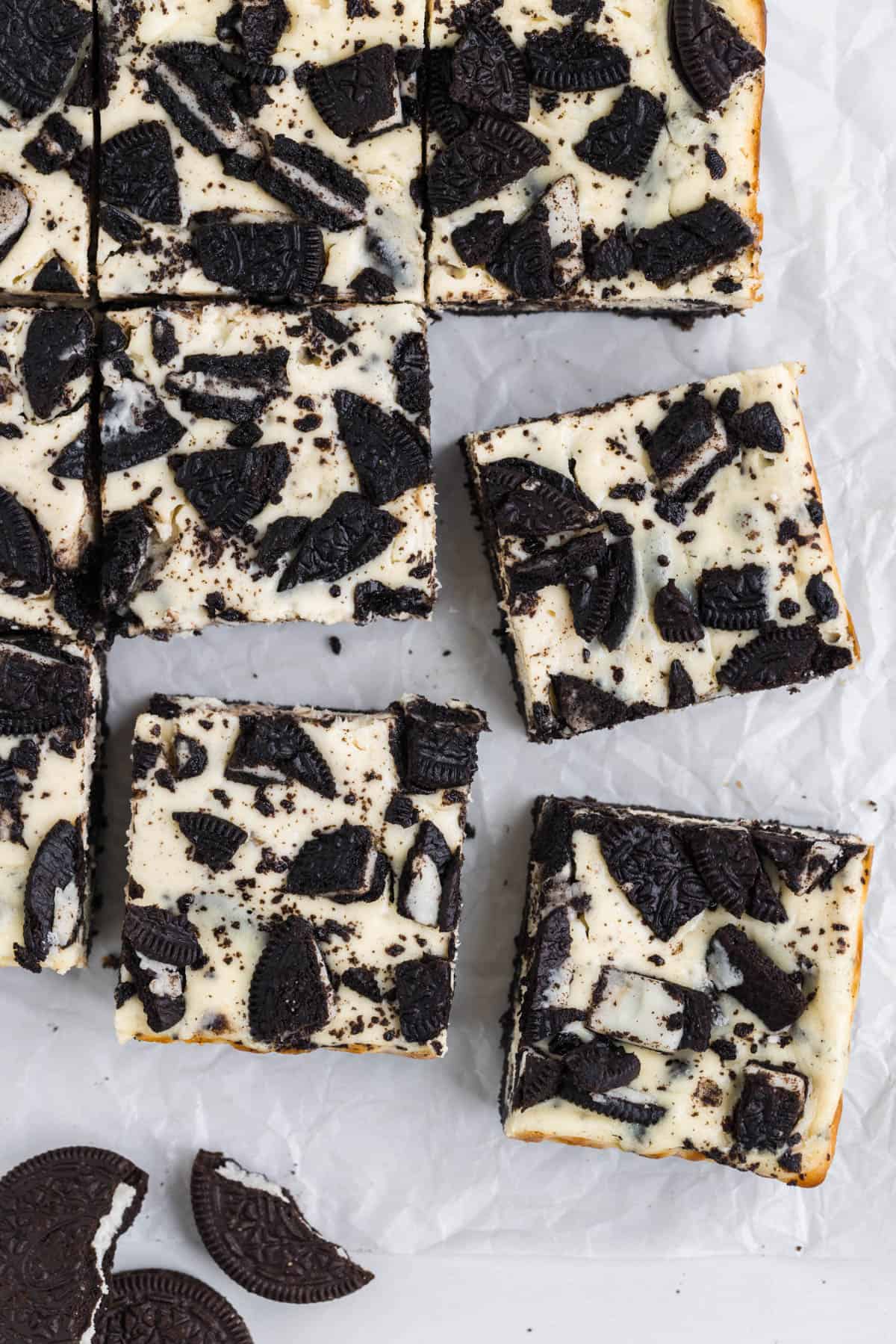 An image of Oreo cheesecake bars cut into squares on parchment paper.